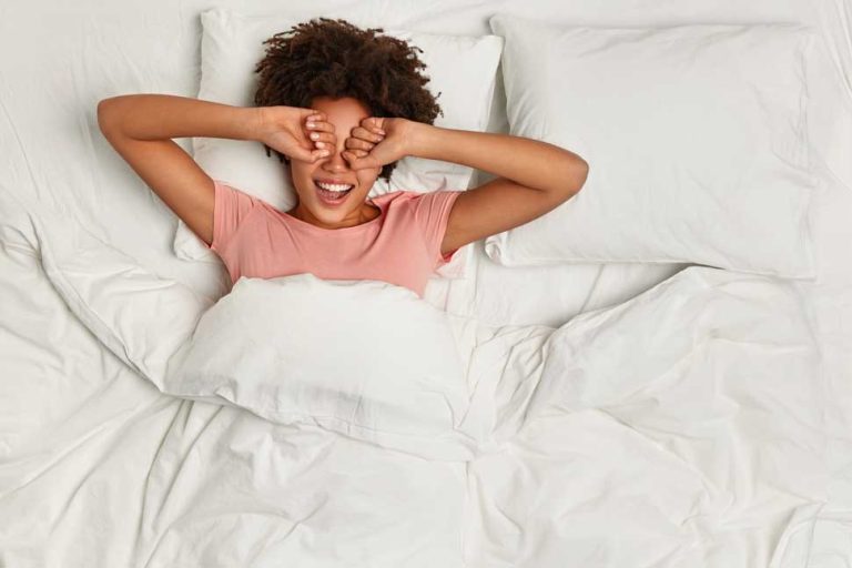 Young woman lying in bed waking from sleep